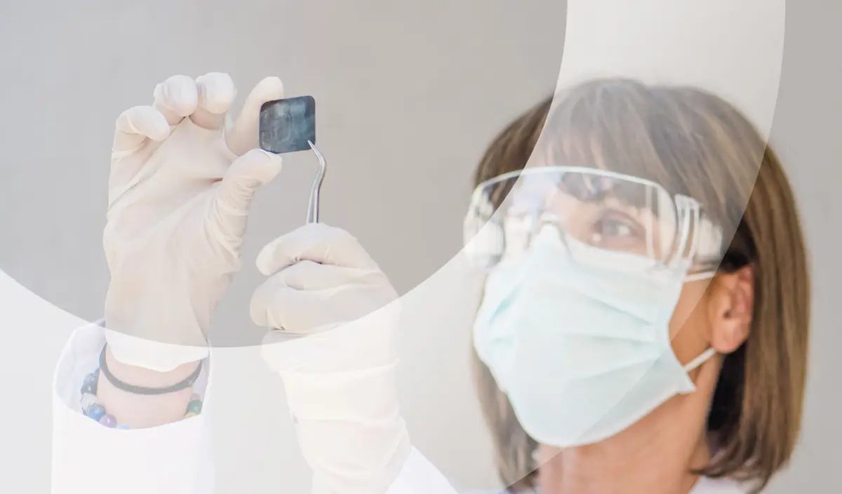 Una profesional con mascarilla y gafas de protección revisando una radiografía